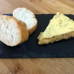 Tortilla de patatas poco cuajada y servida con unas rebanadas de pan