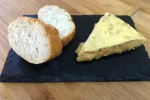 Tortilla de patatas poco cuajada y servida con unas rebanadas de pan