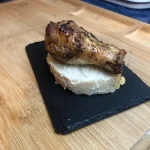 Tapa de alita de pollo asada al horno sobre rodaja de pan
