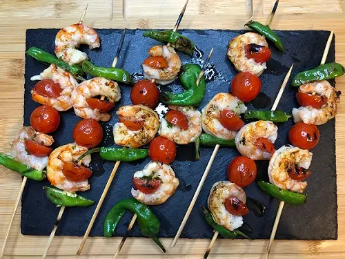 Brochetas de gambas con tomates cherry y pimientos del padrón.