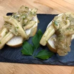 Tapa de calamar a la cebolla y vino blanco sobre una rebanada de pan.