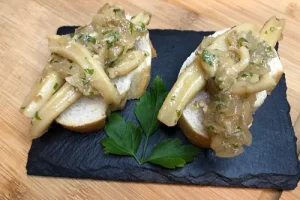 Tapa de calamar a la cebolla y vino blanco sobre una rebanada de pan.