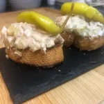 Tapa de ensaladilla rusa sobre pan tostado y coronada con una guindilla