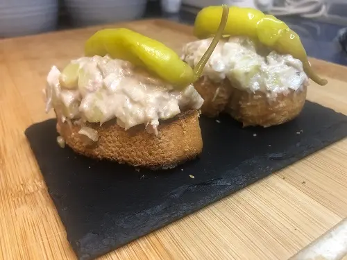 Tapa de ensaladilla rusa sobre pan tostado y coronada con una guindilla