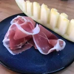 Plato con una rodaja de melón acompañada de jamón