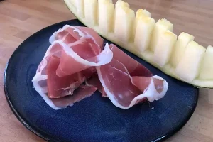 Plato con una rodaja de melón acompañada de jamón