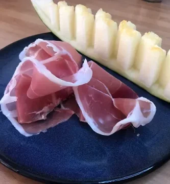 Plato con una rodaja de melón acompañada de jamón