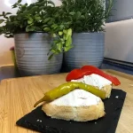 Paté de atún servido sobre pan tostado y coronado con una guindilla verde.