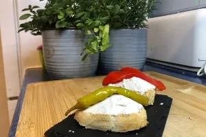 Paté de atún servido sobre pan tostado y coronado con una guindilla verde.