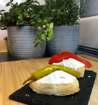 Paté de atún servido sobre pan tostado y coronado con una guindilla verde.